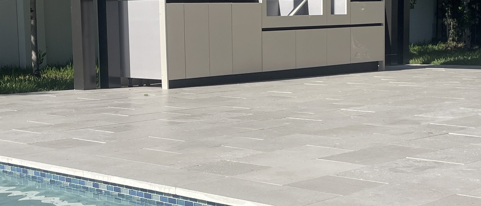LANDIIN outdoor kitchen design beside a pool under a slatted canopy